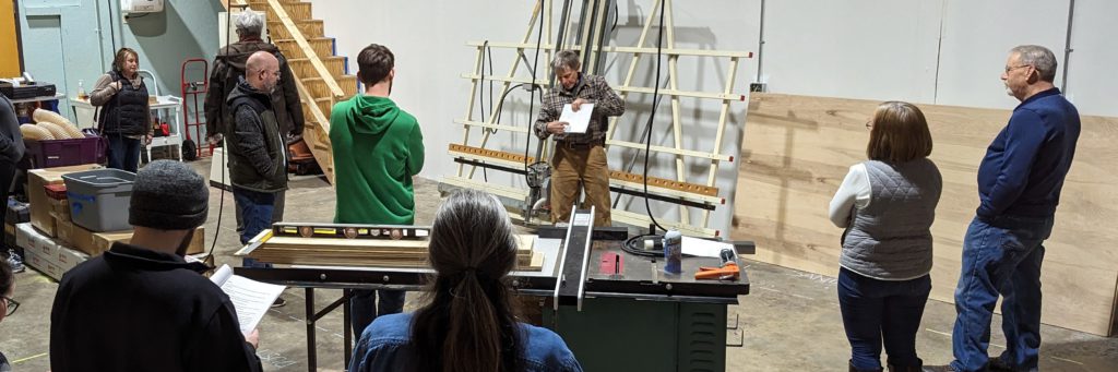 Man demonstrates to crowd use of a panel saw